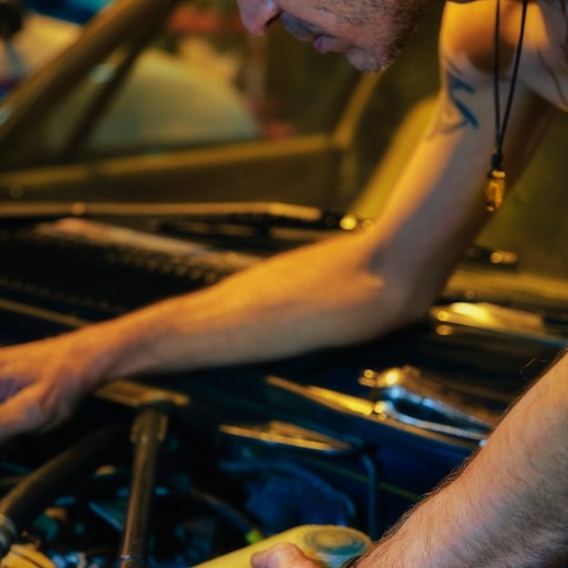 Ein Mann arbeitet an einem Auto, während er den Motorraum überprüft.